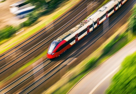 Fast red and white train entering town an aerial view